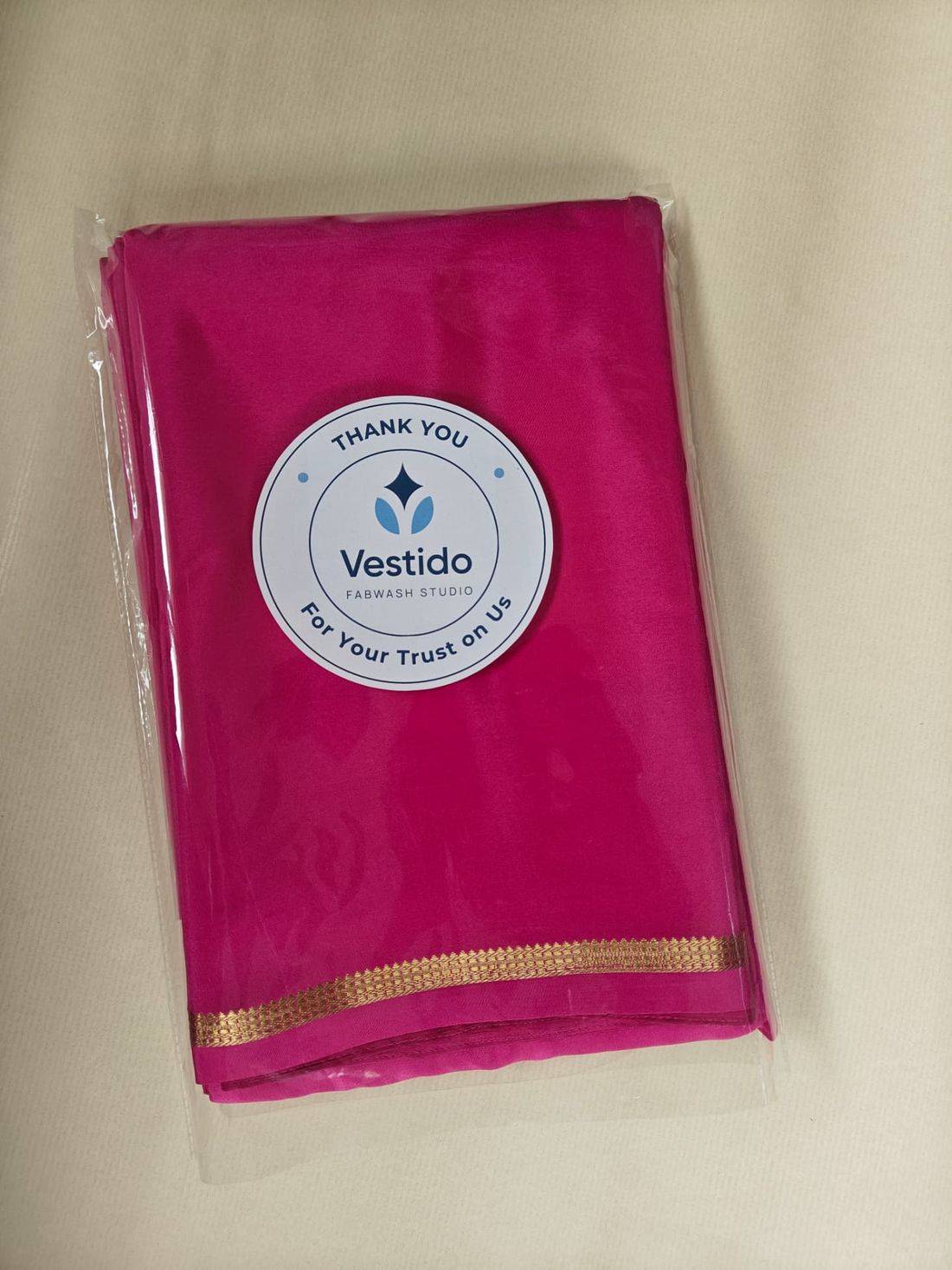 Pink silk saree with gold zari border roll polished, tissue-folded and sealed at Vestido Fabwash Studio Bangalore